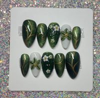 Hand made custom gel press on nails.  These nails are made to order specially for you! Whether you want to go the extra mile for a special event, or just want to feel fancy in your day to day life, these precious custom press on nails are for you. Inspired by the green nature, and flowing waters of Thailand, these nails bring me back to one of my favorite vacation memories. Cat eye polish layered with green jelly give a unique shimmering effect. The 3d aspect of the middle nail gives the illusion of flowing water, and the 3d hand carved flower on the ring finger makes this set super unique. You will surely get compliments on this set!   Please note picture with instructions on how to measure your nails.  See instructions when choosing "custom" in size options