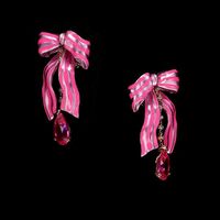 A playful pair of Breton ribbon bow earrings in recycled rose pink aluminium with hand-painted neon pink enamel, 18k rose gold vermeil with 18k gold posts, intricately bezel and prong set with two laboratory-grown and created fuchsia pink sapphires with white diamonds.