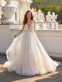 Layered ballgown with beaded lace bodice with deep v-neckline and sparkle tulle skirt. Sampled in ivory/latte/nude (pictured,) in size 10. Can be ordered in ivory/latte/nude, or all ivory in sizes 2-28.