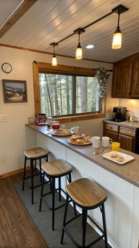 Add a breakfast bar to your small cabin decor for quick meals and casual socializing. Counter space, bar stools, and views of nature make it functional and inviting. Check out more breakfast bar ideas here.