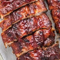 Close-up shot of beautifully caramelized, saucy baby back ribs, cut into individual pieces, displaying their glossy, appetizing appearance.