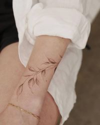 Illustrative style leaves tattoo located on the wrist.