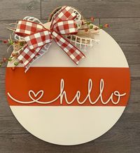 Decorate your front door this fall season with this Hello Door hanger. Painted in cream and burnt orange, this laser cut hello is permanently attached and the door sign is finished with a double bow, natural raffia and seasonal berries. Dimensions are 16 inch diameter and 1/4 thick. Made from cabinet grade MDF and is safe for outside on your front porch or anywhere inside your home. All signs have a UV clear sealer to protect from minor scuffs and scratches.