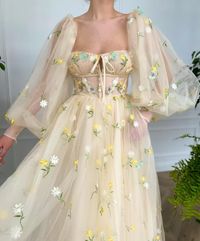 Details:-Soft beige tulle with embroidered daisies and daffodils-Sweetheart neckline with a decorative bow and a small opening in the front-Decorative divider in the bodice-Wide, puffy long sleeves with zippers in the tight cuffs-Tea length-...