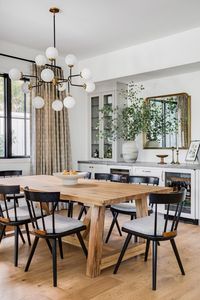 We love the modern farmhouse feel of this dining room. Built in cabinetry adds a sleek touch against rustic wood. + farmhouse + modern farmhouse + farmhouse table + modern chandelier + built in cabinetry + wine fridge | Design by Rosabel Tran Design