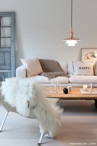 A modern living room with a sofa and white cushions, a pendant light, a setting chair with nice white rug in top of chair. http://www.urbanroad.com.au/