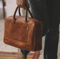 Tan leather briefcase. The Zip-Top brief is a diverse everyday carry. It looks at home in the hands of lawyer or artist.....man or woman. The bag is compact, but still has plenty of room to house laptop, pens, notebooks etc. Two external for easy access as well. Made of full-grain leather and includes detachable strap. From Whipping Post