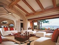 This gorgeous living space draws inspiration directly from its expansive views of the Sardinia bay of Porto Rotondo and the Mediterranean Sea. Architect Savin Couëlle chose a warm, earthy palette, using chestnut beams overhead and terra-cotta floor tiles.