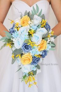 This lovely assortment of is bound to turn heads on your wedding day. This lovely cascading brides’ bouquet from the is an absolutely breathtaking arrangement for any bride to be, in any season. This bouquet is made with light blue roses, dusty blue roses, yellow roses, blue hydrangea and accented and light greenery complete the look and add a delicate realism to this beautiful bouquet. This bouquet is 10” wide, 18” long, and is crafted by our in-house florists without using a foam base to ancho