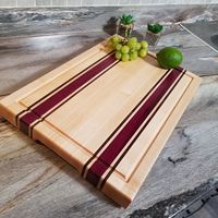 This cutting board is edge-grained with exotic Purpleheart, Walnut pinstriping, and Maple hardwoods. Purpleheart is a native wood from the rainforests of Central and South America and provides a vibrant, colorful contrast to other woods. This board is 1¼” thick and comes with a juice groove, cut in finger holds, and rubber feet. FREE 2-oz. bottle of conditioner wax included with care instructions.