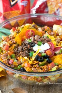 Dorito Taco Salad is a great potluck recipe with seasoned ground beef, lettuce, pinto beans veggies and Doritos all sauced up with a zingy dressing.