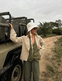 Elevate your safari experience with these casual and chic summer outfit ideas! Perfect for women traveling to South Africa, Tanzania, and Namibia, our guide features elegant and comfortable clothing options that are ideal for the wild, just like this cool safari outfit with a beige cardigan, an olive green vest and matching trousers.