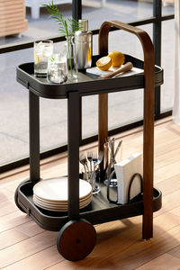 Upgrade your space with the charm and versatility of the Bellamy Black Serving Cart with Tray. With a tiered design, the black metal cart features two rimmed trays; a curved, dark brown wood handle; and two rubber-rimmed wheels. 