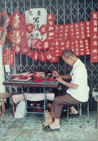 Old Chinese sign and banner writer at Tan Quee Lan Street, circa 1980s. Copyright. All rights reserved. Cyril T C Ng. (With permission from Cyril T C Ng.)