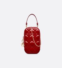 The Lady Dior Call'in Dior phone holder is both sophisticated and ingenious. Crafted in cherry red Cannage patent calfskin, the accessory features detachable D.I.O.R. charms. The phone holder may be carried by hand or worn crossbody thanks to its handle and chain strap..