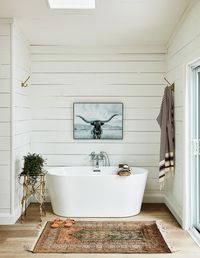 A tub sits in an alcove of the principal bedroom offering a view of the lake. A skylight was placed above for stargazing. | Photographer: Stacey Brandford | Designer: Sam Sacks