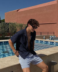 This casual summer fashion outfit features a navy button-up shirt paired with striped shorts, embodying effortless chic and relaxation.   #SummerStyle #Poolside #TerracottaTextures #BlueHues #FashionGoals #RelaxationMode #pooloutfit #beachoutfit #palmspring