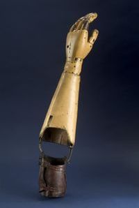 Prosthetic arm with wooden fingers & metal joints is a Carnes model from the late nineteen-teens (WWI era). It is named for William Carnes, an amputee who fashioned the first workable shoulder harness design around 1915