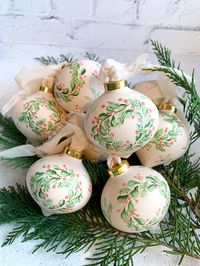 FREE SHIPPING! This is a one-of-a-kind, ceramic, hand-painted Christmas ornament. Beautifully crafted, this heirloom piece of art will hopefully be passed along for years to come. Includes a gorgeous gold cap and hangs from a raw-edged cream silk ribbon. Set on a soft coral background, the wreath of berries and leaves takes center stage with pretty shades of green, peach and coral.  Each ornament is sealed in a matte finish, for protection. This acorn shaped ornament about measures 3" in diameter, and along with the cream ribbon, you will receive an ornamental gold hook which you can use instead of the ribbon, if you'd like.  You may order the BEAUTIFUL WOOD-BASED STAND WITH CURVED METAL HANGER to display your ornament for an extra charge of $12. Select this option when ordering. Your orna