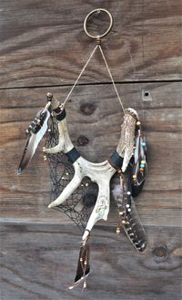 This dreamcatcher is one of a kind, handcrafted using naturally shed deer antler. The feathers are turkey and duck, and they hang from leather cord. All beads are made from wood. Holes were drilled into back of antler to run webbing through. The designs on the antler were made using a wood burner, with some painted color accents.  It all hangs from a brass ring with hemp cord.  Antler measures approx. 9.5"x9"x12" Total length approx. 30"  Total width approx. 9.5"