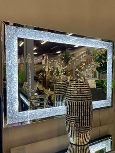 two vases sitting on top of a table in front of a mirror with lights