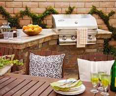 an outdoor kitchen with grill, sink and table set up for two people to eat