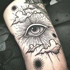 an all seeing eye tattoo on the arm with clouds and stars around it in black ink