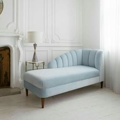 a blue couch sitting in front of a window next to a clock on a wall