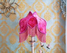 a pink lamp sitting on top of a table next to a vase with flowers in it