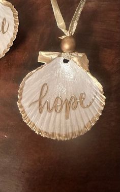 two seashells with the word hope written on them hanging from a wooden table