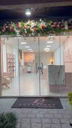 the entrance to a nail salon with flowers hanging from it's glass walls and doors