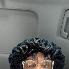 a man wearing glasses and a knitted hat in the back seat of a car