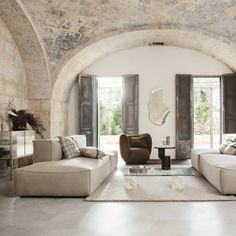 a living room filled with furniture and a large window next to a stone wall covered in windows