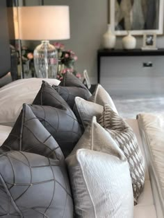 the pillows are piled on top of each other in front of a bed with flowers