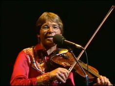 a man that is standing in front of a microphone with a violin on his shoulder