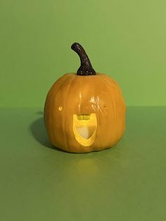 a yellow pumpkin with a smiley face on it's side sitting on a green surface