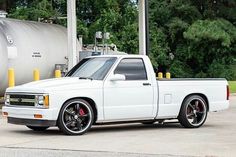 a white pickup truck parked in front of a gas station with tanker tank behind it