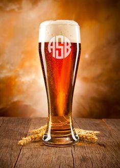 a glass of beer sitting on top of a wooden table