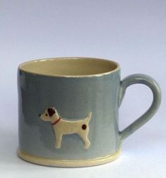 a coffee cup with a dog on the front and side is sitting on a white surface