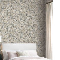 a white bed sitting under a window next to a wallpapered headboard and foot board