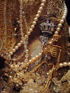 an assortment of beads and jewelry on display in a store window, with the skeleton wearing a tiara