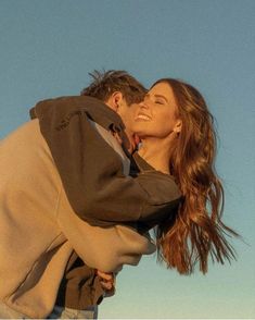 a man and woman embracing each other in front of a blue sky