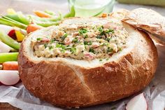 a close up of a bread bowl with vegetables in the background