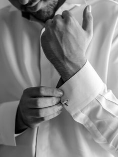 black and white photograph of a man adjusting his collar on his dress shirt, taken from the waist up