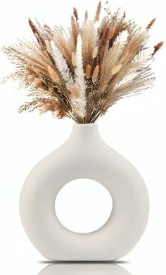 a white vase with some dried plants in it