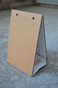 an open cardboard box sitting on the ground with two holes in it's side