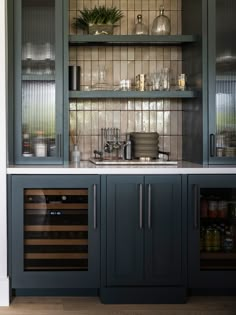 a kitchen with gray cabinets and glass front cupboards filled with bottles, wine glasses and other items