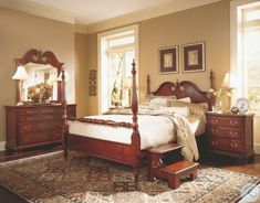 a bedroom with a bed, dressers and mirror in it's center area