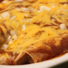 an enchilada with cheese and onions in a white dish