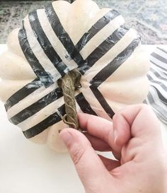 a person is holding an old key in front of a pumpkin wrapped in black and white stripes